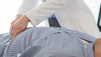 Doctor analyzing abdomen of patient in examination room at hospital.